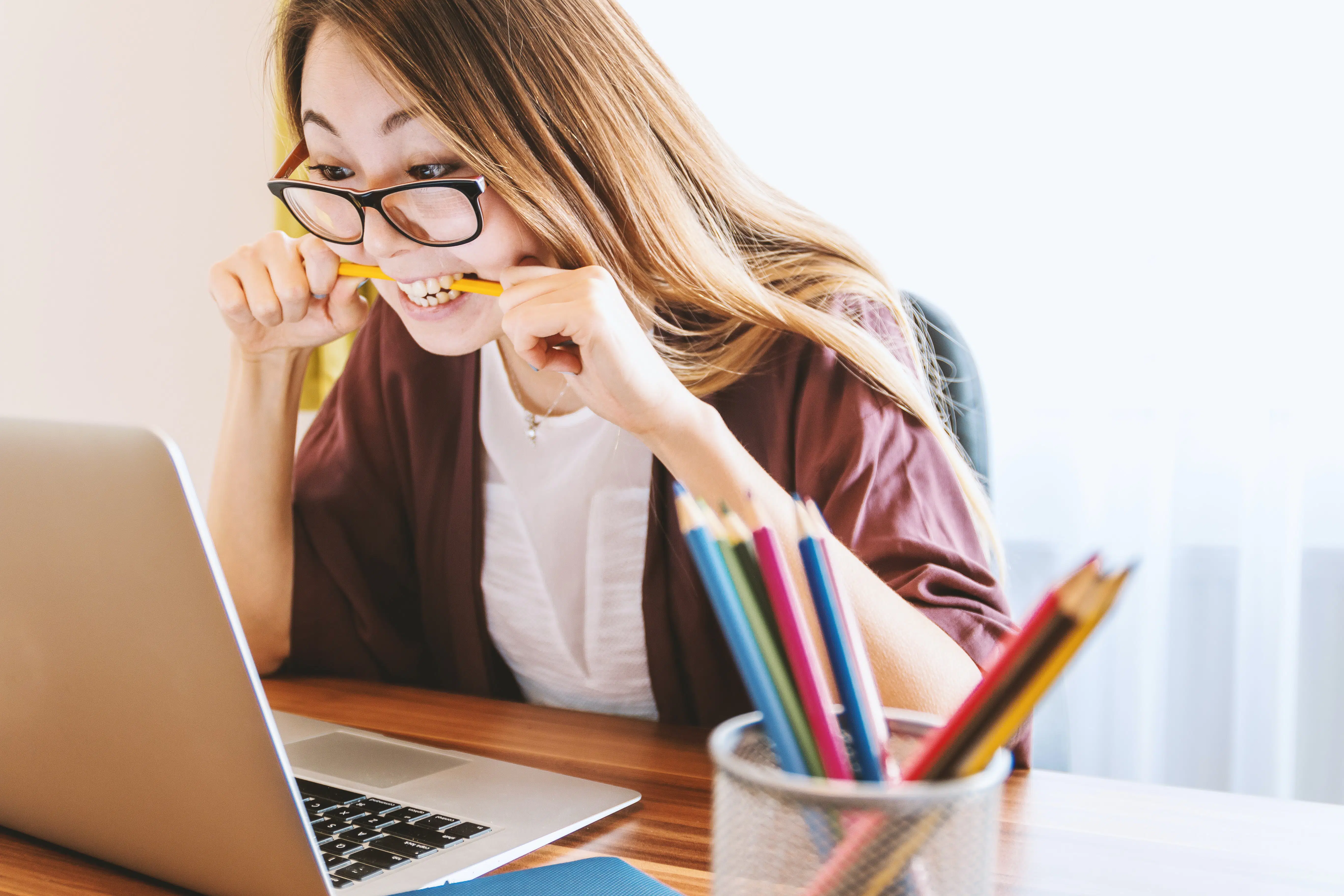 young lady on computer chewing pencil